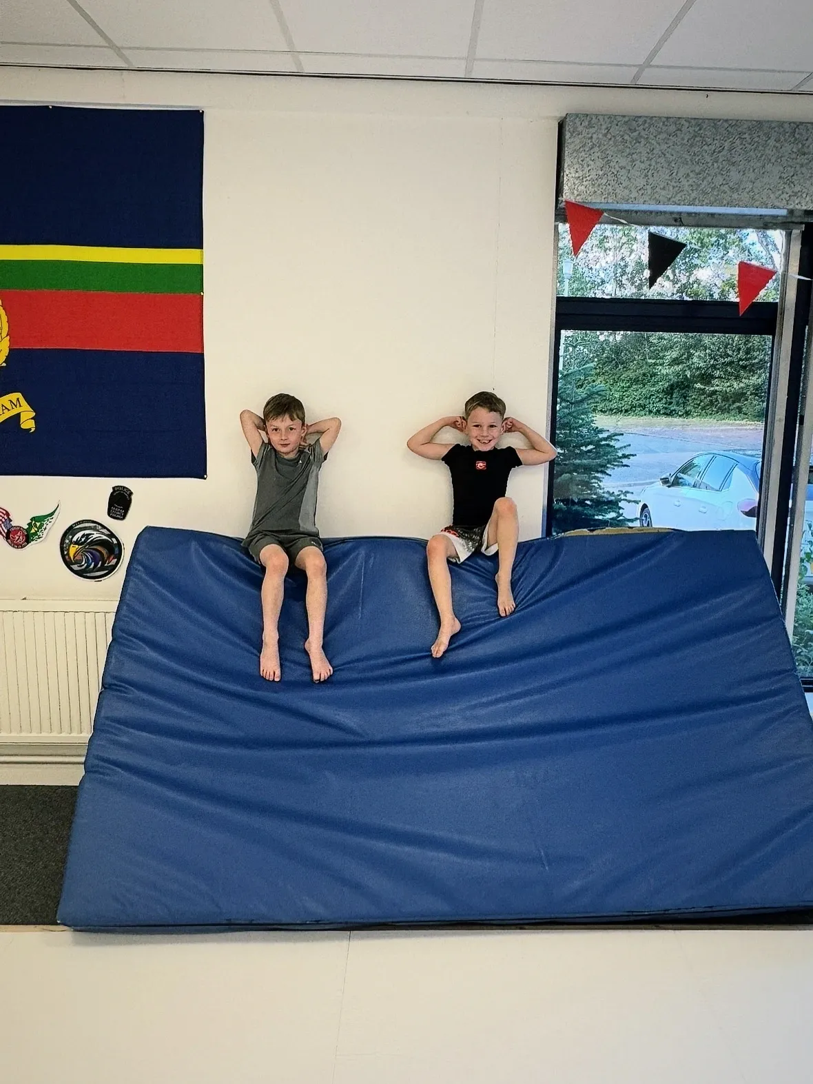 Two kids sitting on a blue mat.