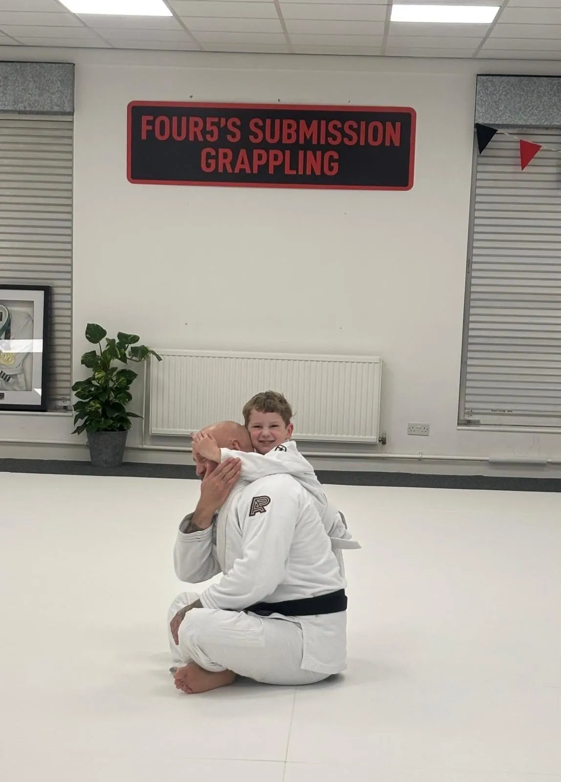 Child practicing grappling with adult instructor.
